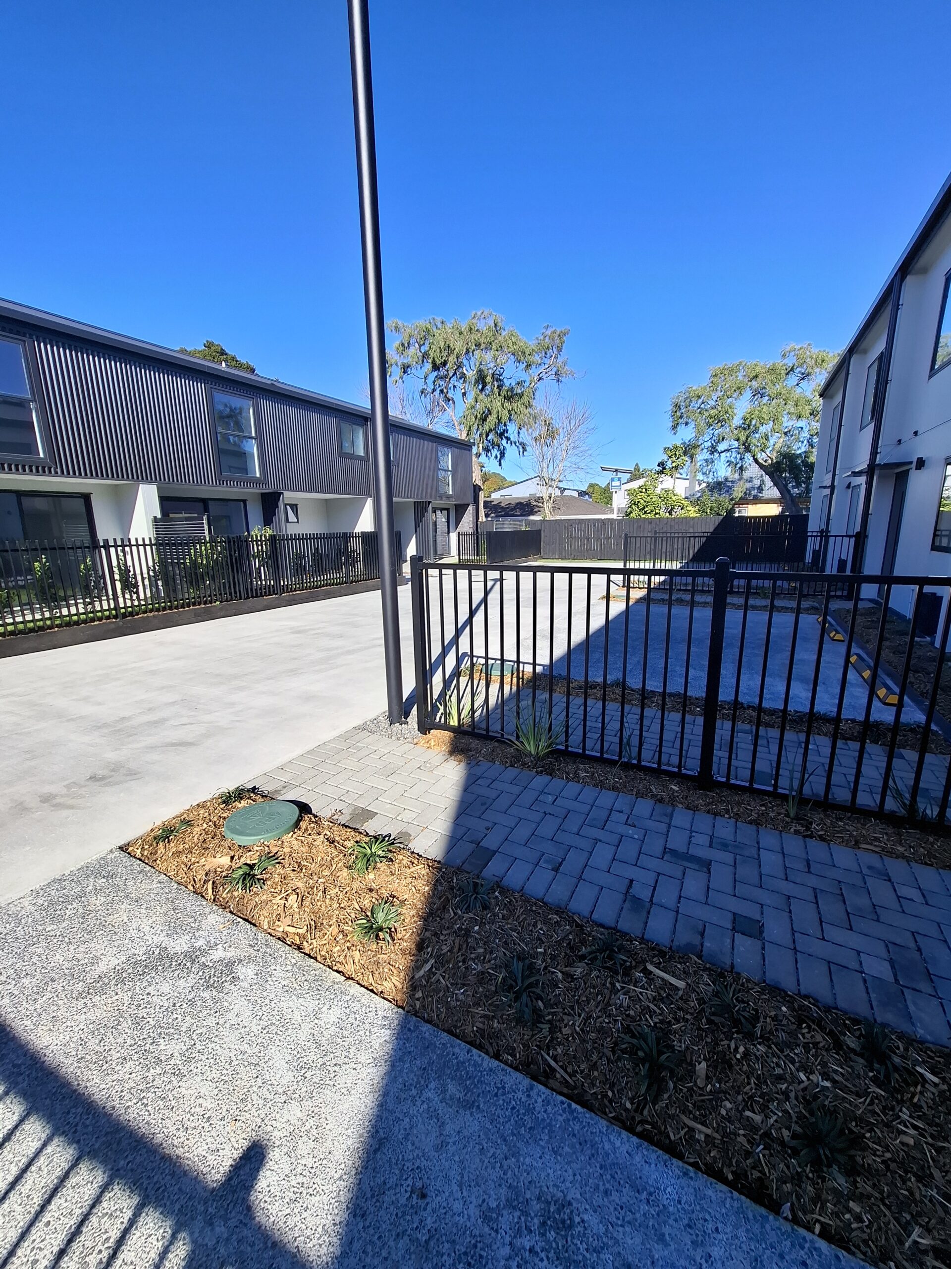 APD StormPit chamber lid set flush in a landscaped garden bed beside the finished accessway