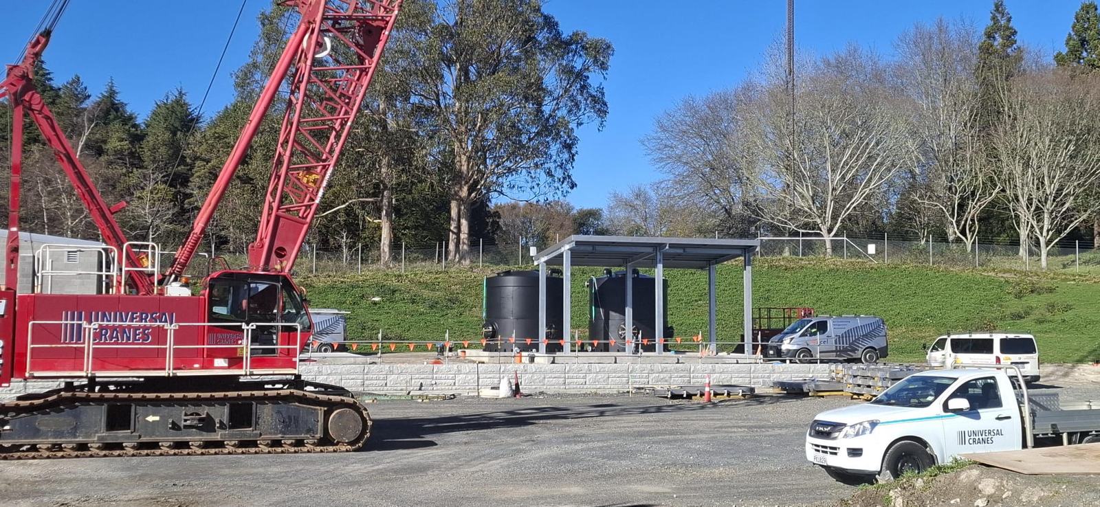 Two HazSure HDPE tanks installed under a steel canopy at the completed Pukete inlet works, with site plant on the forecourt